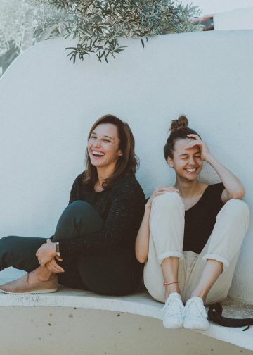 Two Women Sitting on White Bench